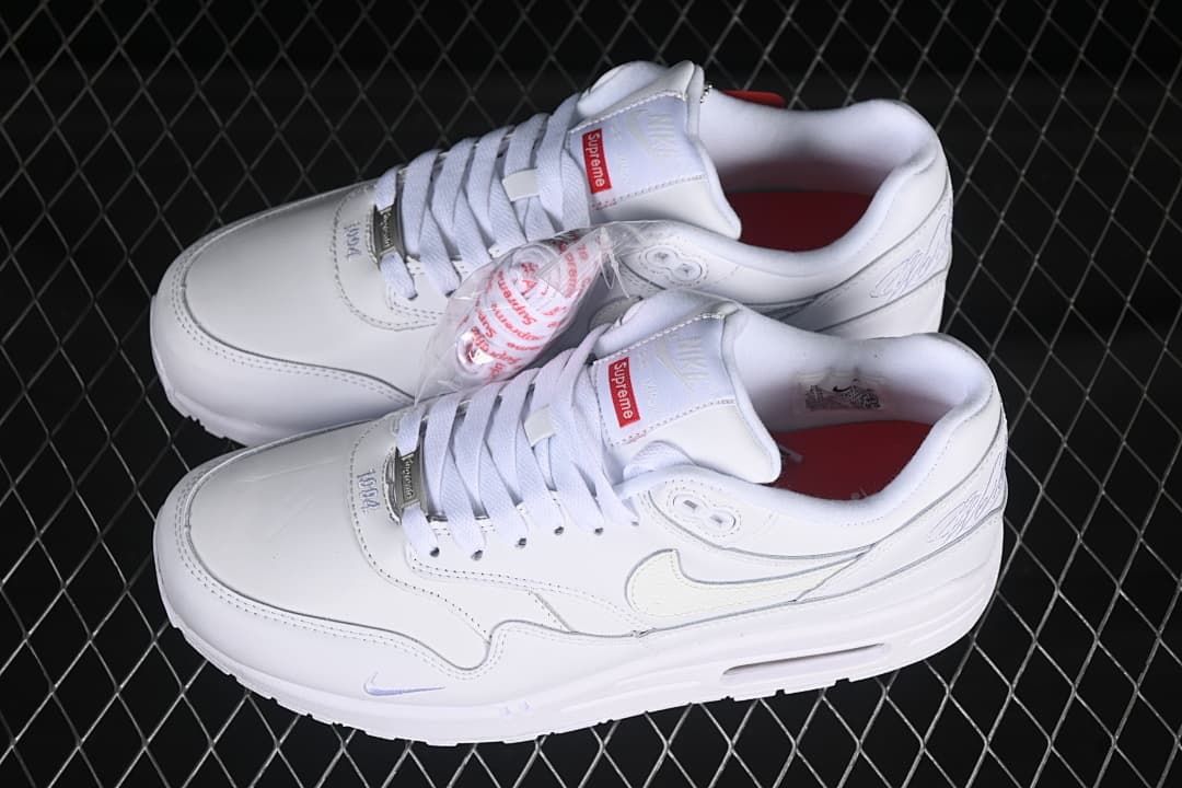 Pair of white sneakers with red insoles and a clear accessory packet