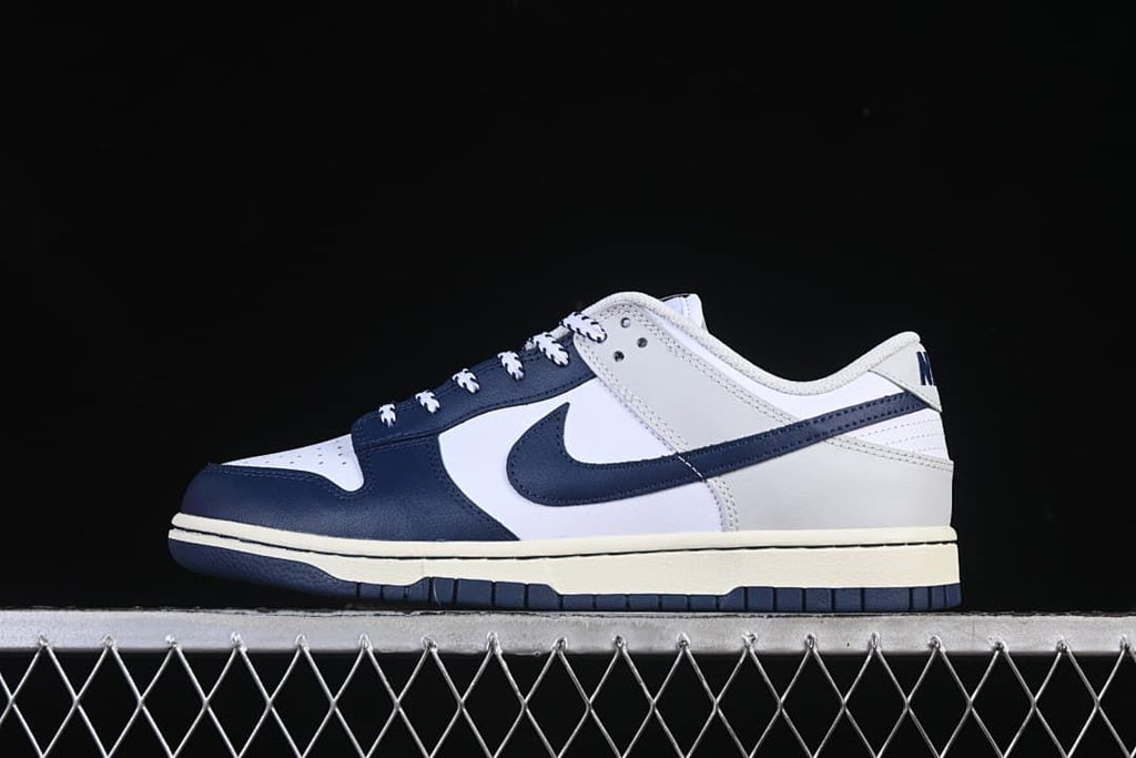 Side profile of a navy, white, and light gray Nike SB Dunk Low sneaker