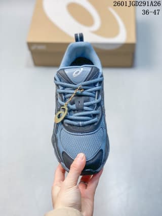 Front view of blue and grey ASICS GEL-NYC RGD sneakers with a branded shoe box in the background.
