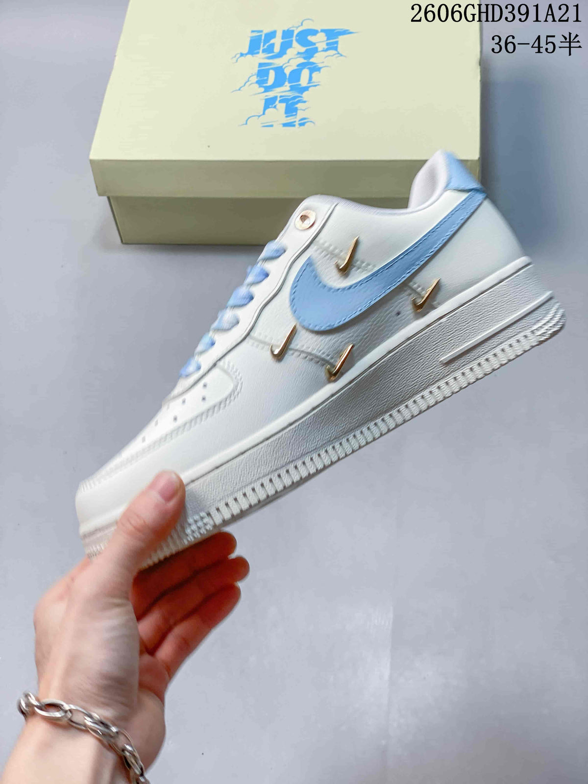Side view of the white low-top sneaker with a light blue Swoosh and gold-tone accents
