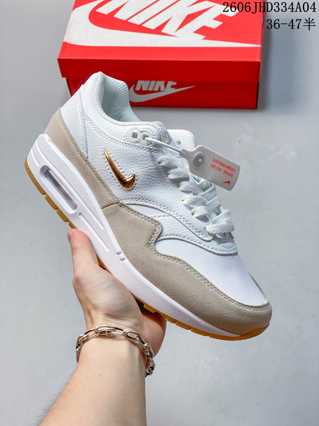 White Nike Air Max 1 sneaker with red Swoosh detailing and a gum-colored outsole.