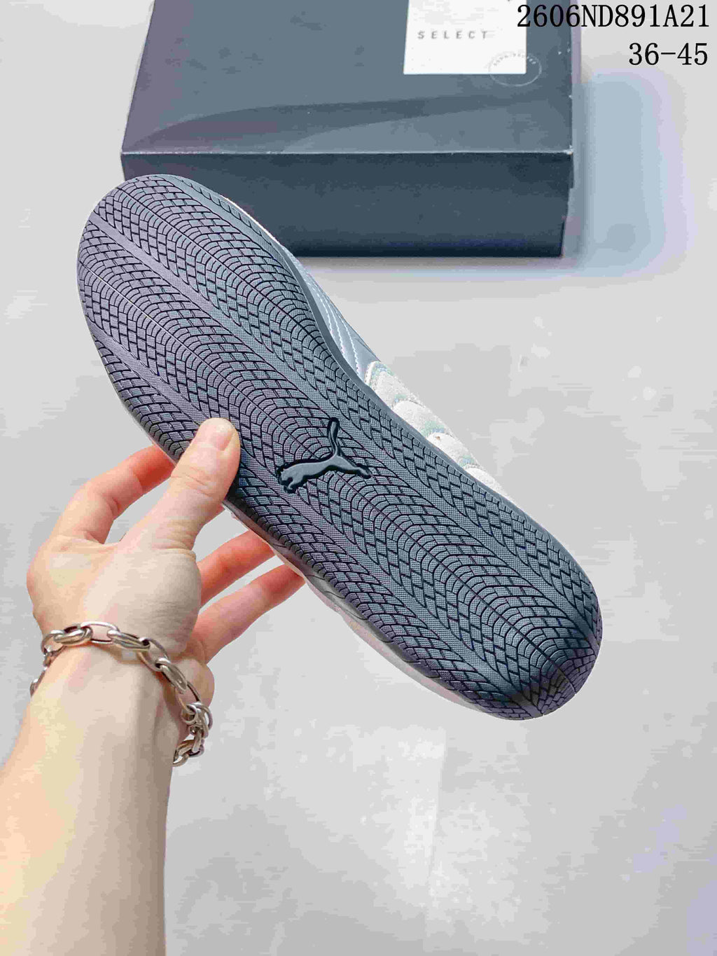 Close-up of the dark patterned outsole on a light gray Puma Speedcat OG sneaker