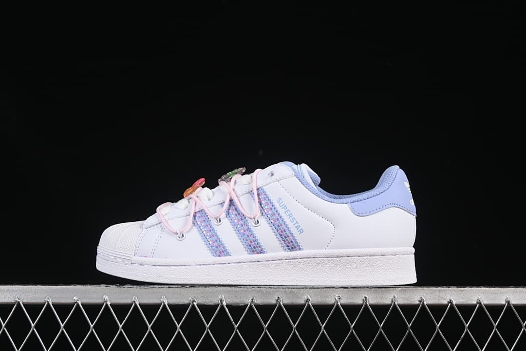 Side view of white adidas Superstar II sneakers with pastel iridescent stripes and pink lace details
