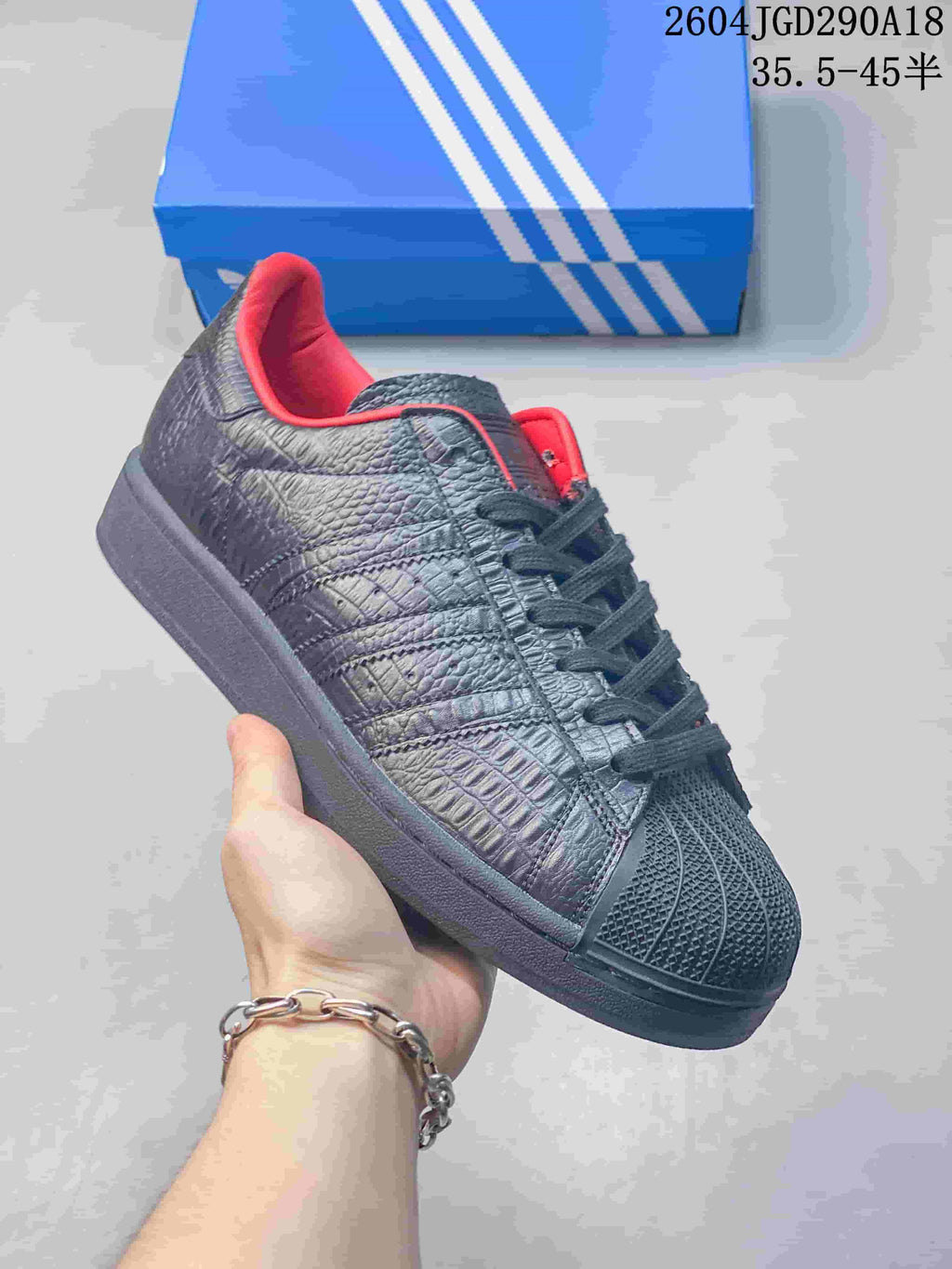 Angled close-up of the textured side panels and red collar lining on a black Superstar 2 sneaker