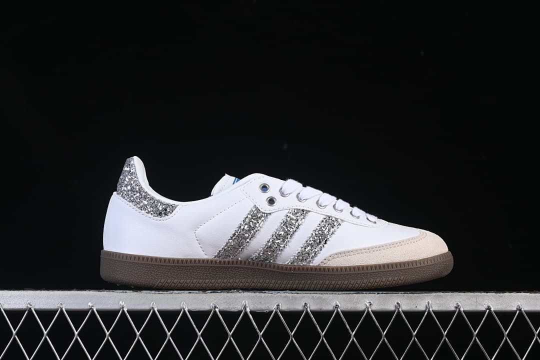 Side profile of a white sneaker with silver glitter-effect stripes and heel accent.