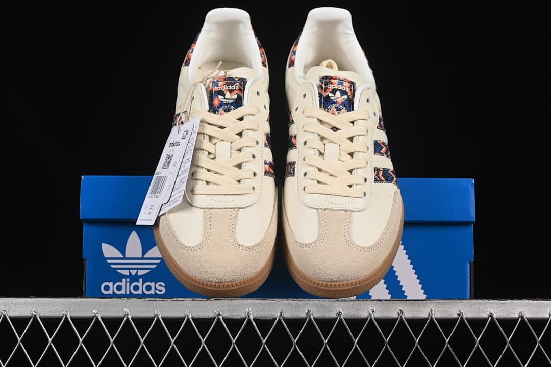 Front view of the pair of cream patterned sneakers displayed on a blue box