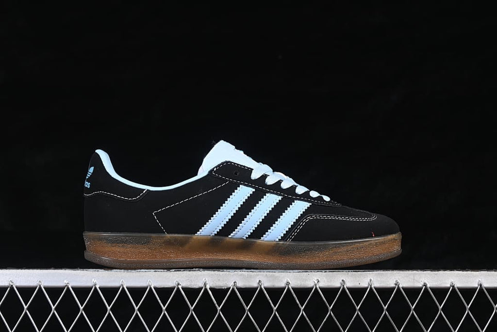 Side profile of the black low-top sneaker with light blue stripes and gum-colored sole
