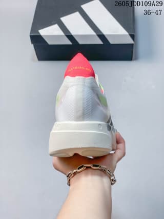 Rear view of the white running shoe showing the red heel accent, textured upper, and white sole.