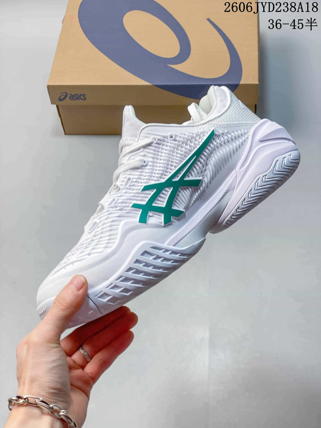 Side view of the white shoe with green ASICS logo and textured upper
