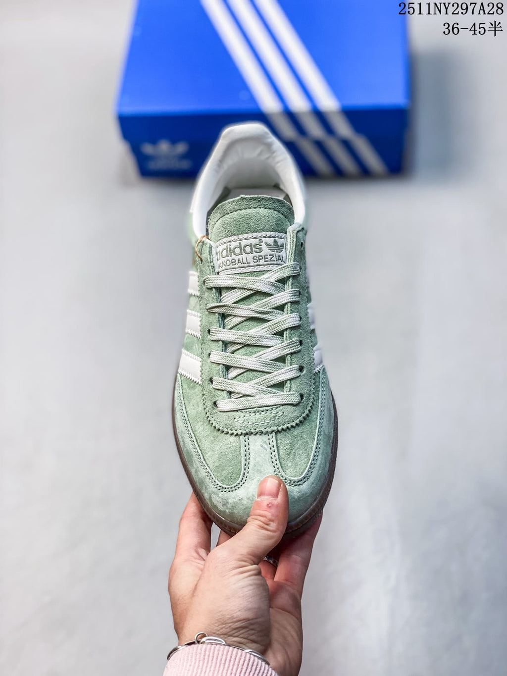 Front view of a pale green adidas Handball Spezial sneaker with white laces and toe detailing.