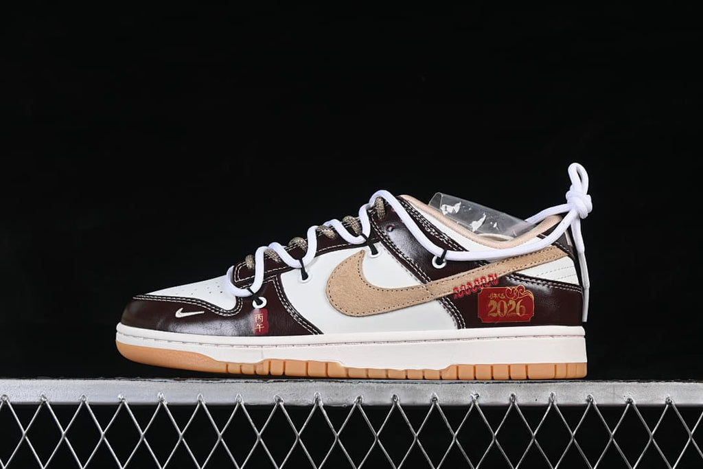 Side view of a cream, dark brown, and tan low-top sneaker with decorative red-and-gold accents