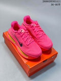 Pair of hot-pink Nike Vomero Premium running shoes with black Swoosh details and thick multicolor-accented soles, pictured on an orange shoe box.
