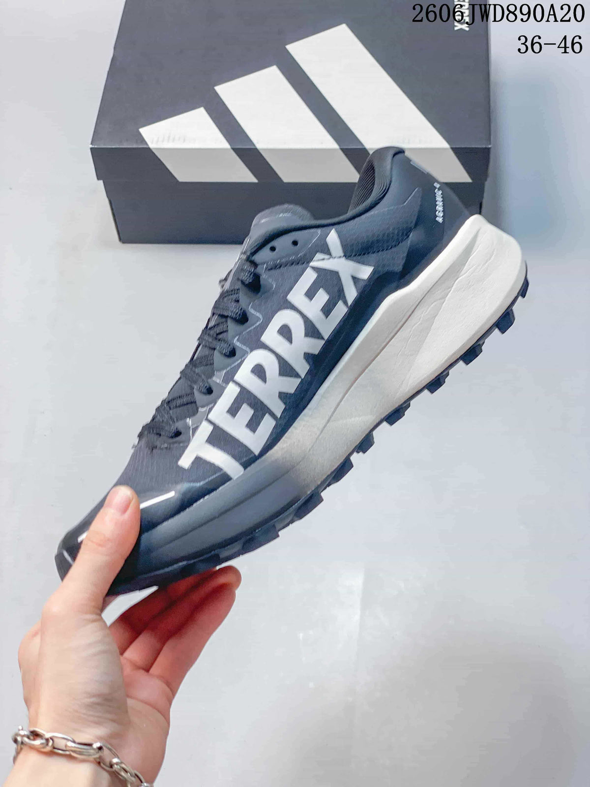 Side view of a gray Terrex trail shoe with white lettering and a sculpted midsole