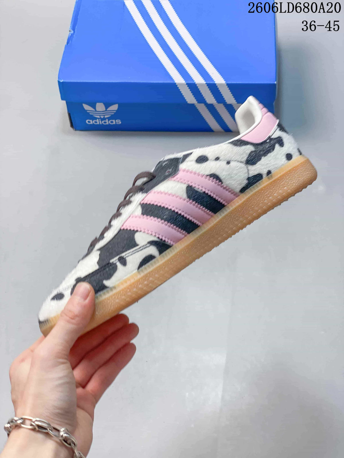 Side view of the Adidas Samba OG showing cow-print panels, pink stripes, and a gum-colored sole