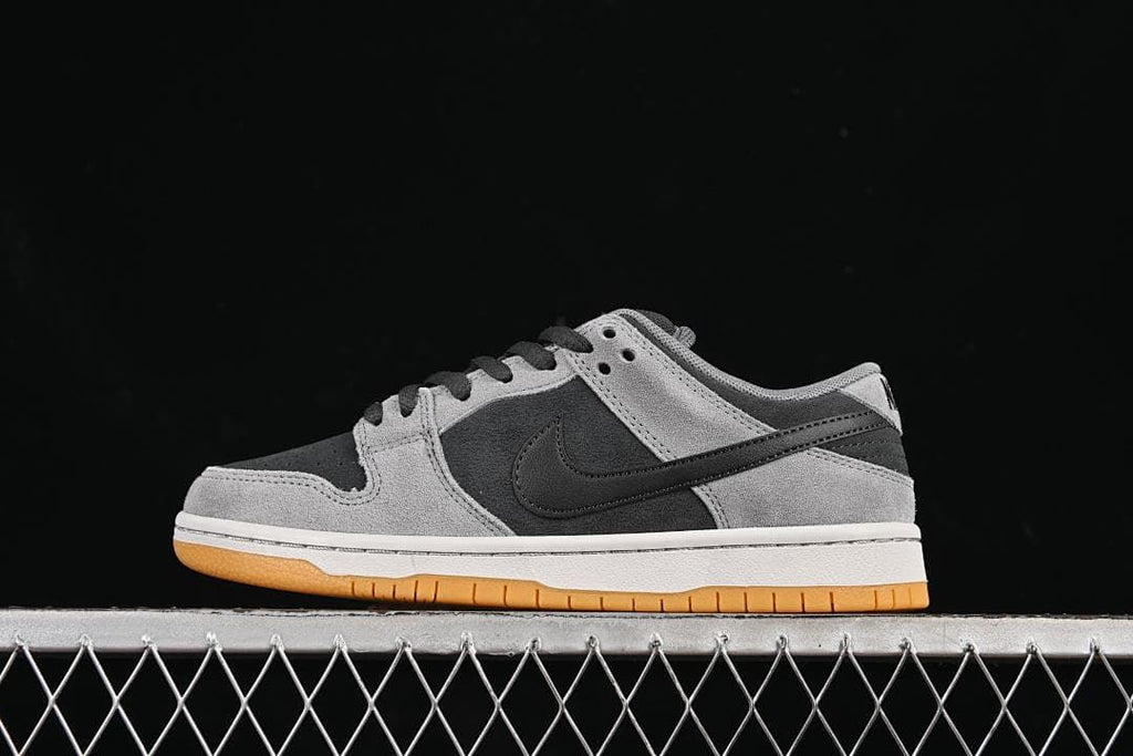 Side view of grey and black Nike SB Dunk Low sneakers with a white midsole and gum outsole