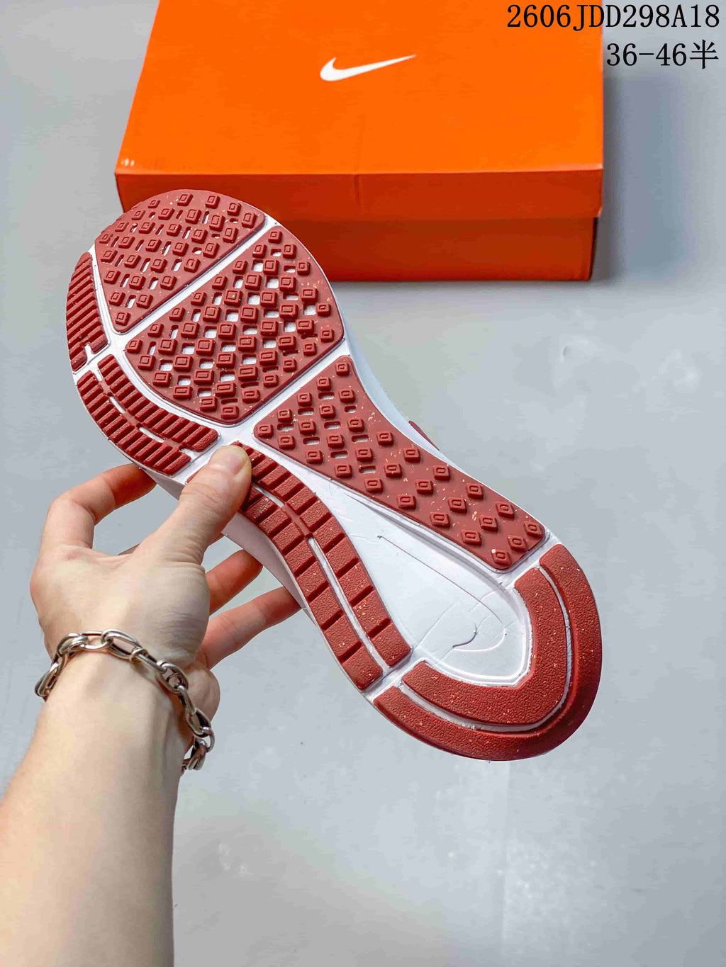 Underside of the running shoe showing a red rubber outsole with segmented tread