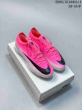Pair of pink Nike Mercurial soccer cleats with black Swoosh details, shown on a shoe box.