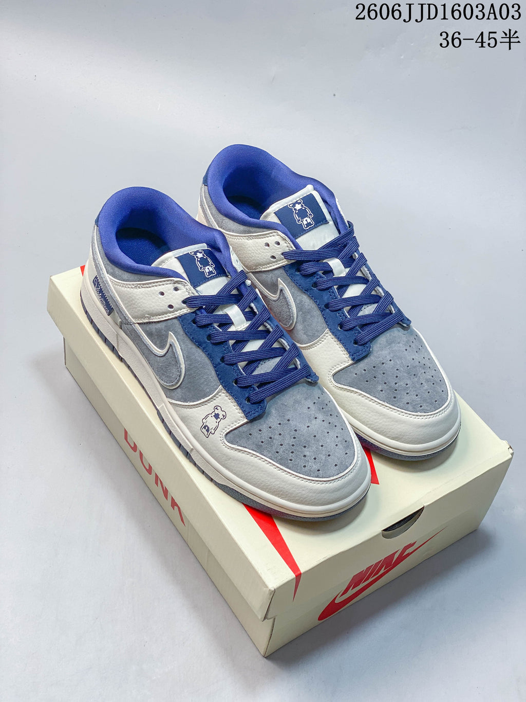 Pair of blue, grey, and off-white Nike SB Dunk Low sneakers displayed on a shoe box