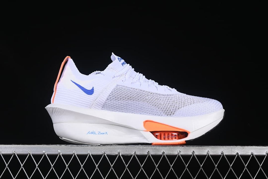 Side view highlighting the white upper, blue Swoosh and orange forefoot detail.