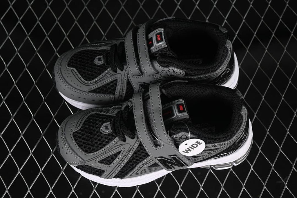 Pair of black and gray kids’ sneakers with hook-and-loop straps and a visible wide-fit tag.