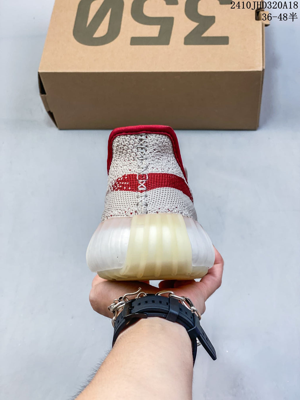 Rear view of a cream sneaker with red heel details and a ribbed sole