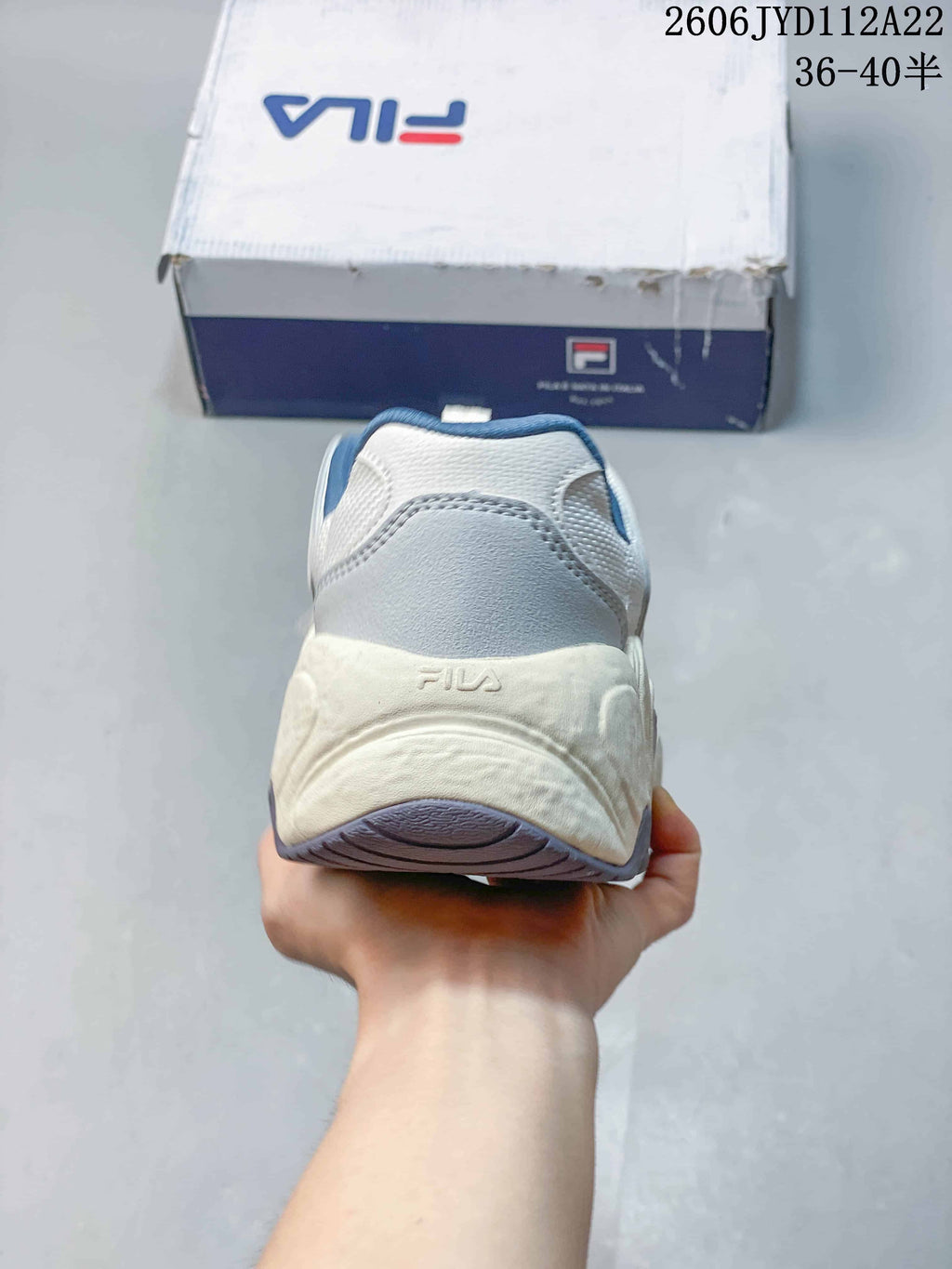 Rear view of a white and blue FILA sneaker with a chunky sole