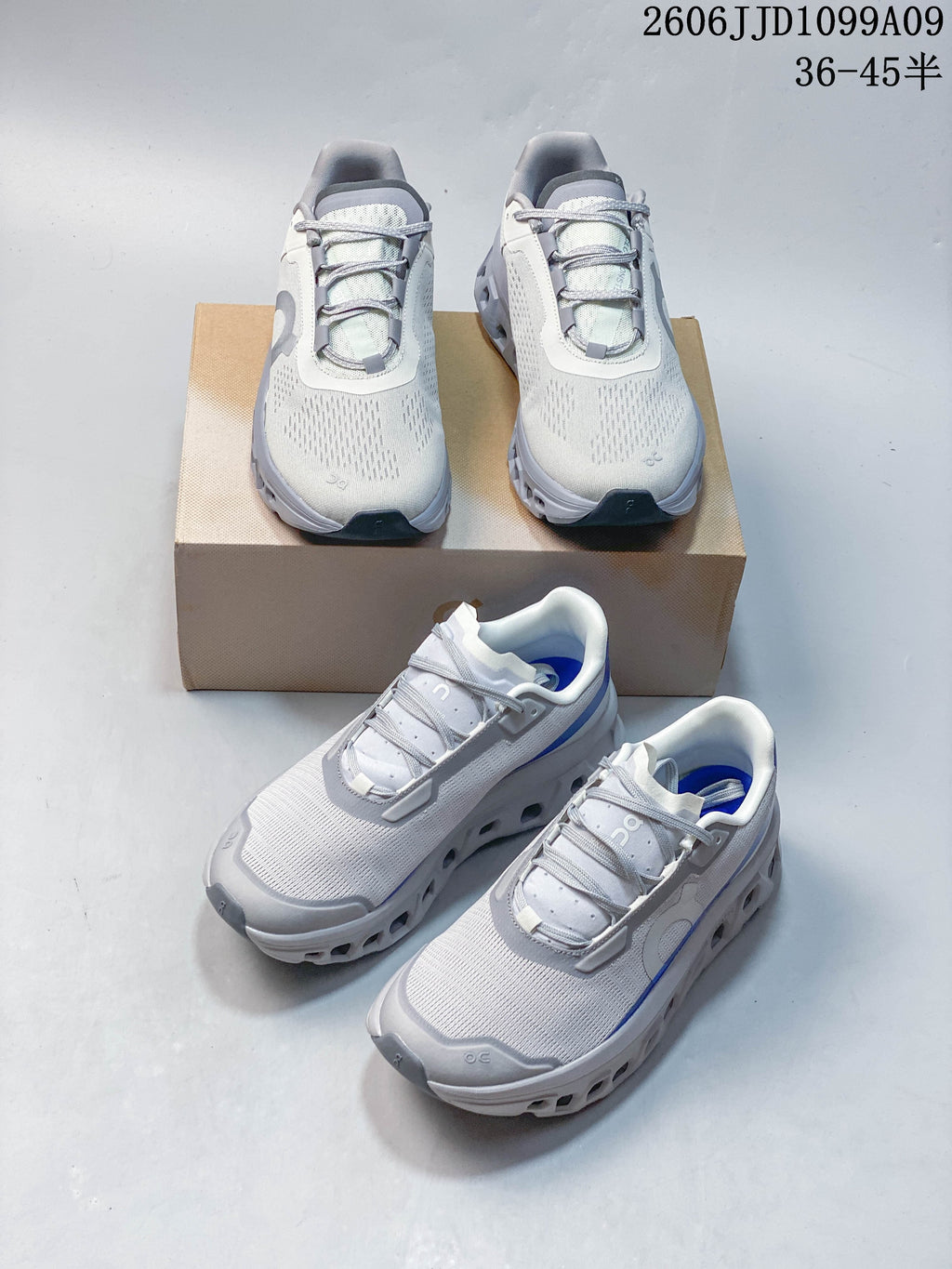 Two On Cloudmonster Void colorways displayed together: light gray with gray detailing and white with blue accents.
