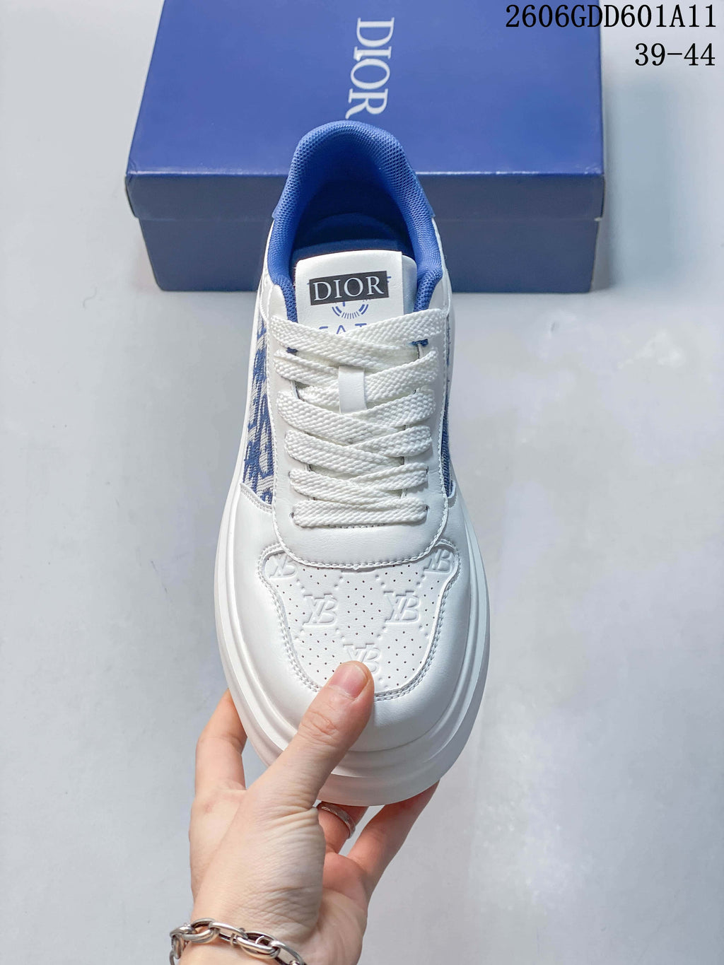 Front view of the white lace-up sneaker with a perforated toe panel and blue collar; image marking shows sizes 39–44.