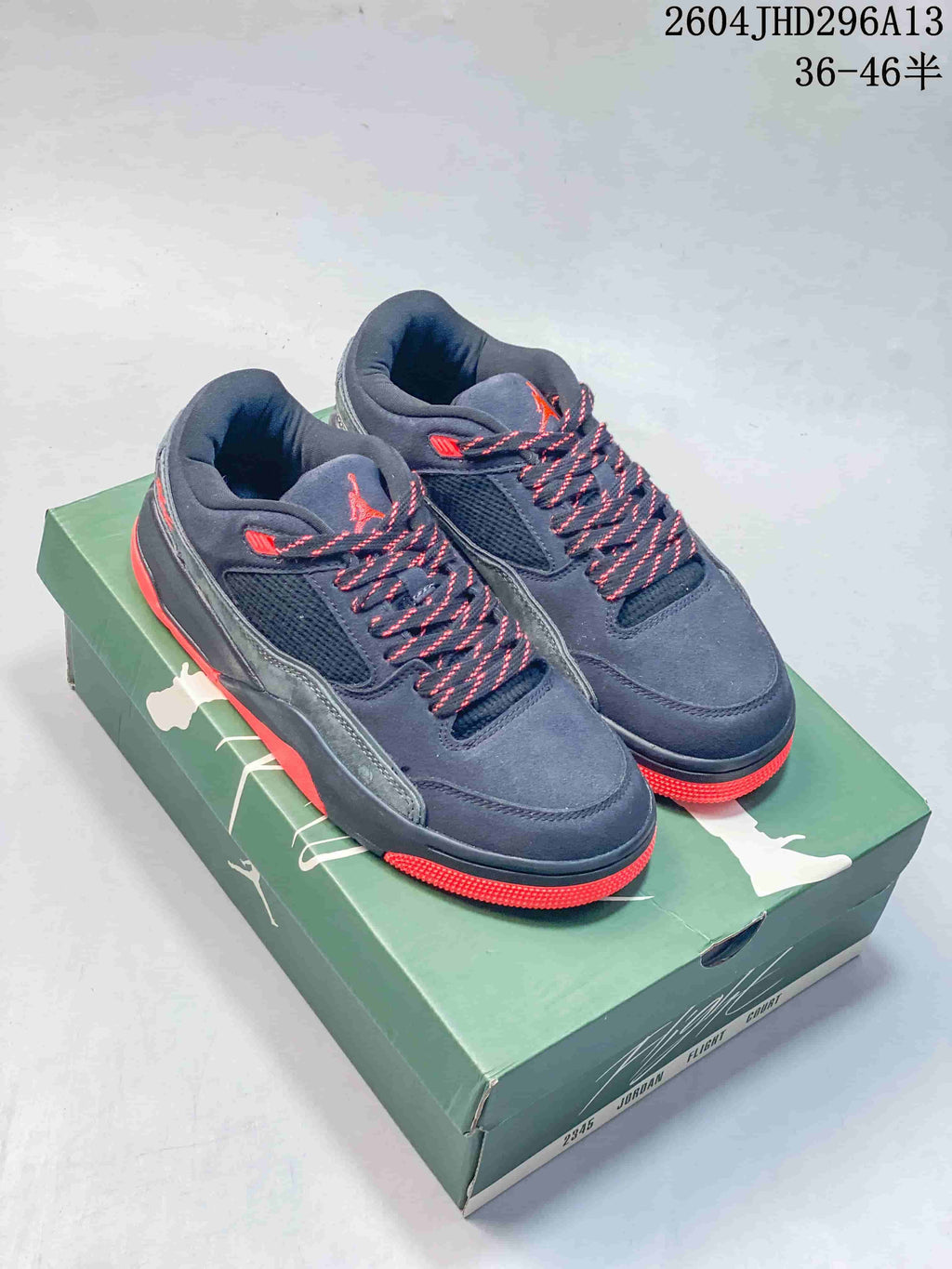 Pair of navy and gray Jordan low-top shoes with red accents on a green Flight shoebox.
