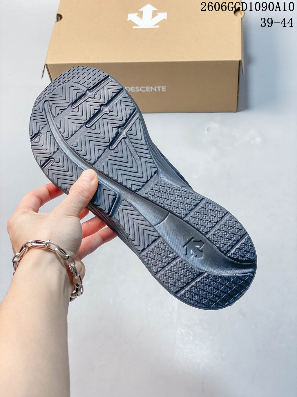Close-up of the patterned outsole on a dark gray Descente sneaker; image text lists sizes 39–44.