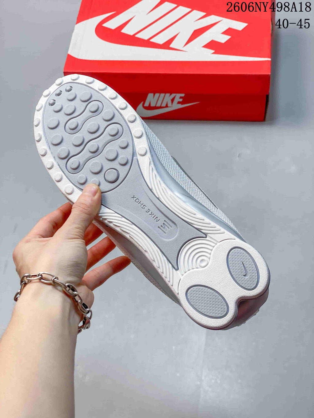 Underside of a white and silver sneaker showing its patterned outsole