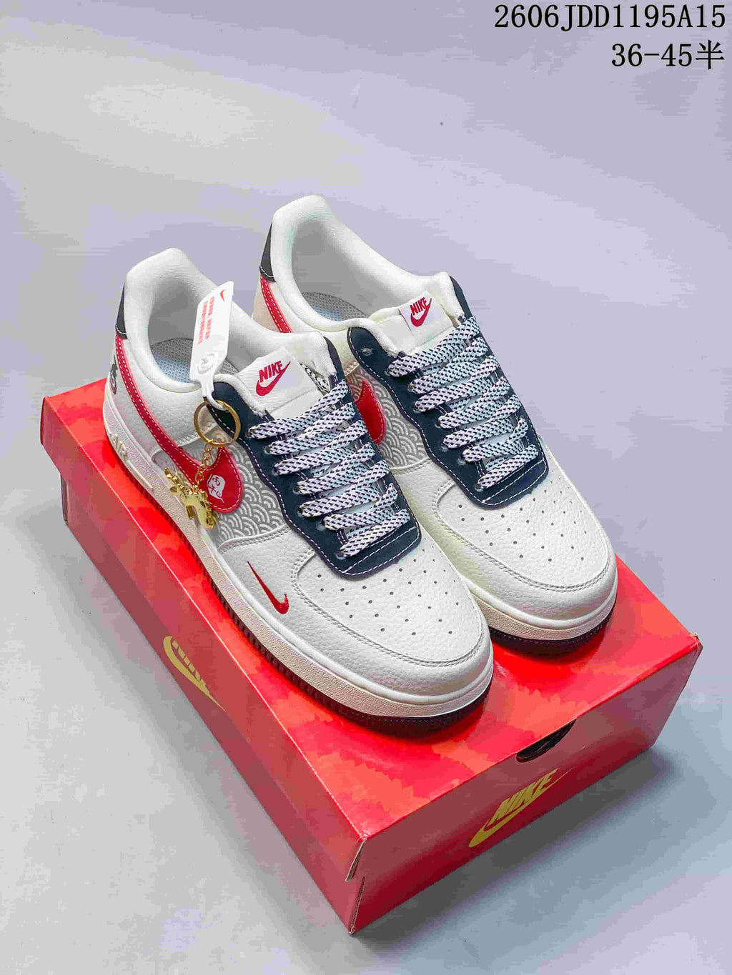 Pair of white, red and navy Nike Air Force 1 Low sneakers with patterned panels and decorative charms