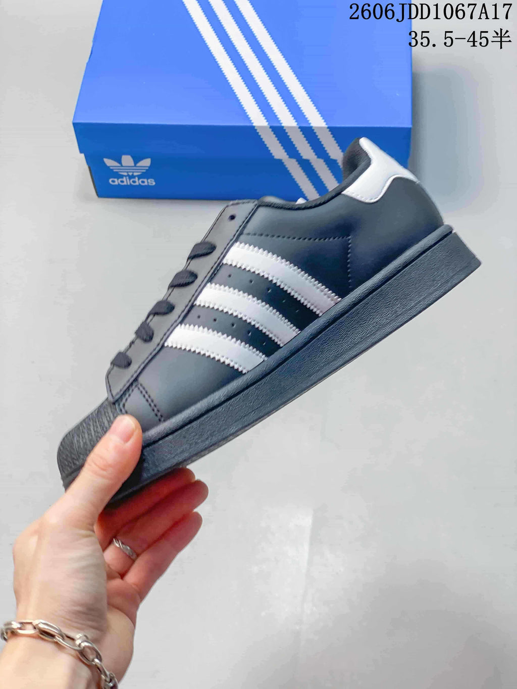 Side profile showing the charcoal upper, white stripes, and shell toe