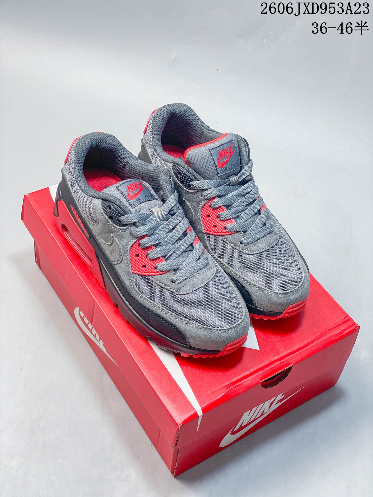 Gray and red Nike Air Max 90 sneakers displayed on a red Nike shoe box