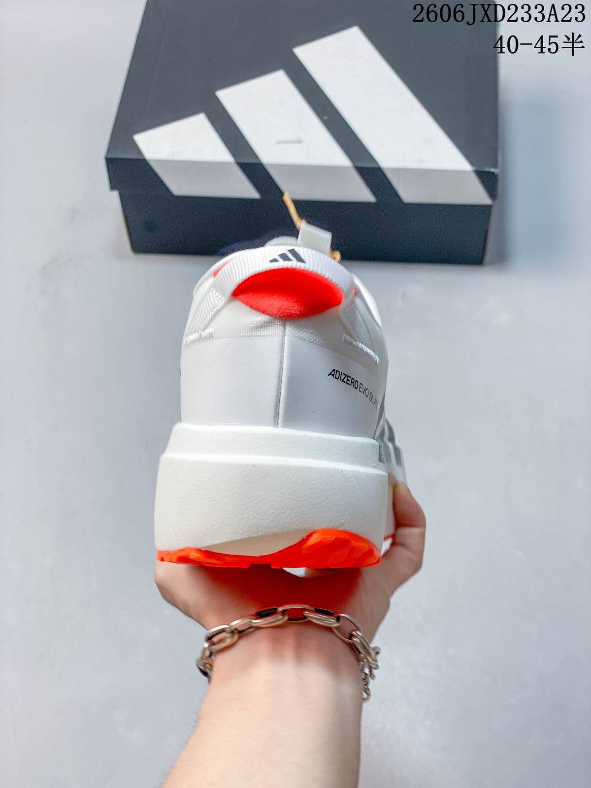 Rear view of the white shoe showing the heel branding and orange outsole
