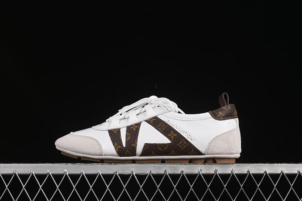 Side view of the white, brown, and beige sneaker on a display surface.