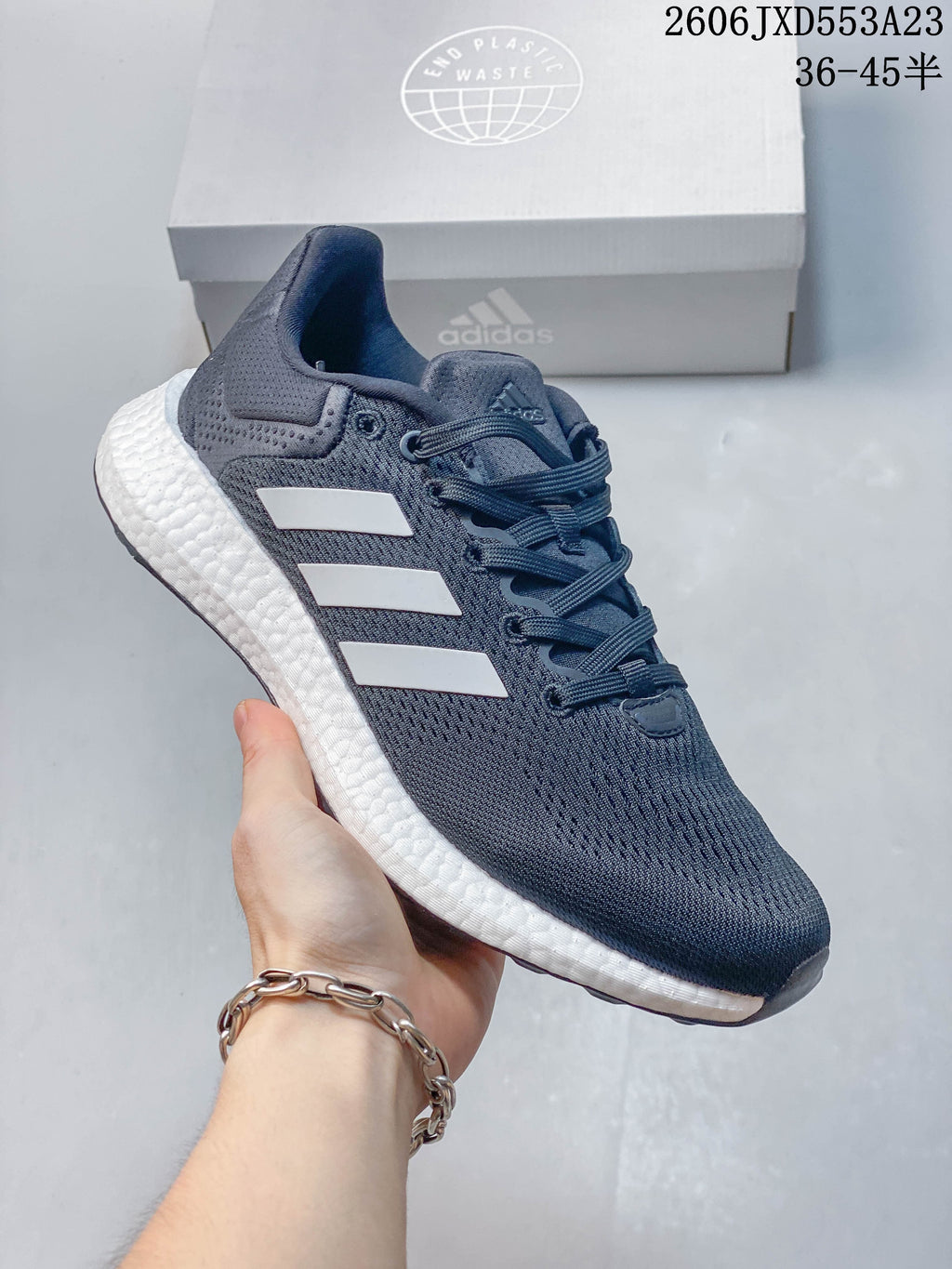Angled side view of a navy Adidas PureBoost 21 running shoe with white stripes and a textured white midsole.