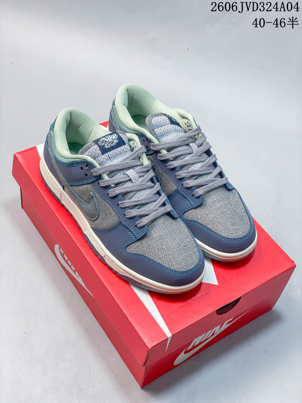 Pair of gray and blue Nike Dunk Retro SE low-top sneakers displayed on a red shoebox