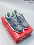 Pair of gray and blue Nike Dunk Retro SE low-top sneakers displayed on a red shoebox