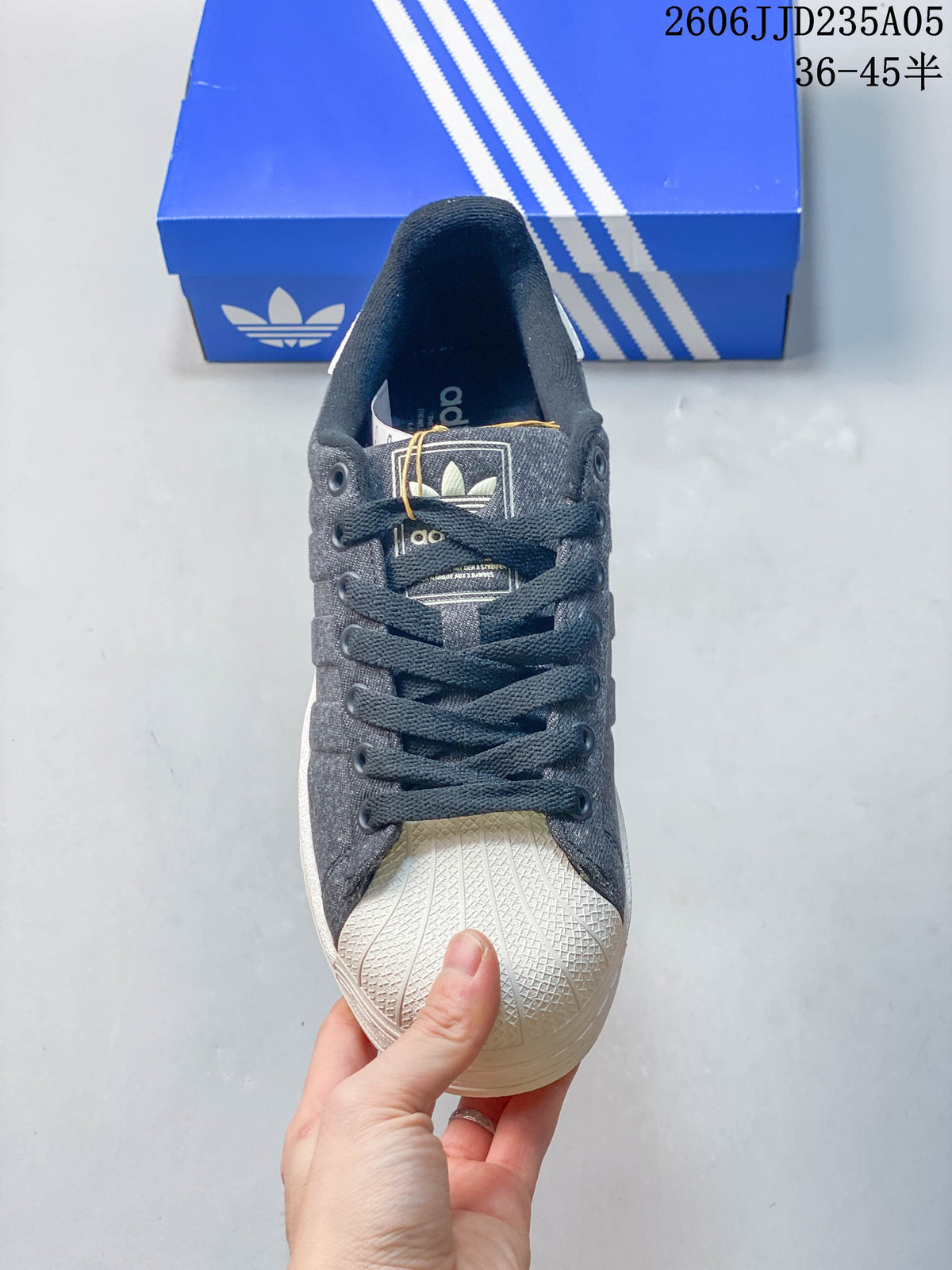Front view of a gray sneaker with dark laces and a white textured shell toe