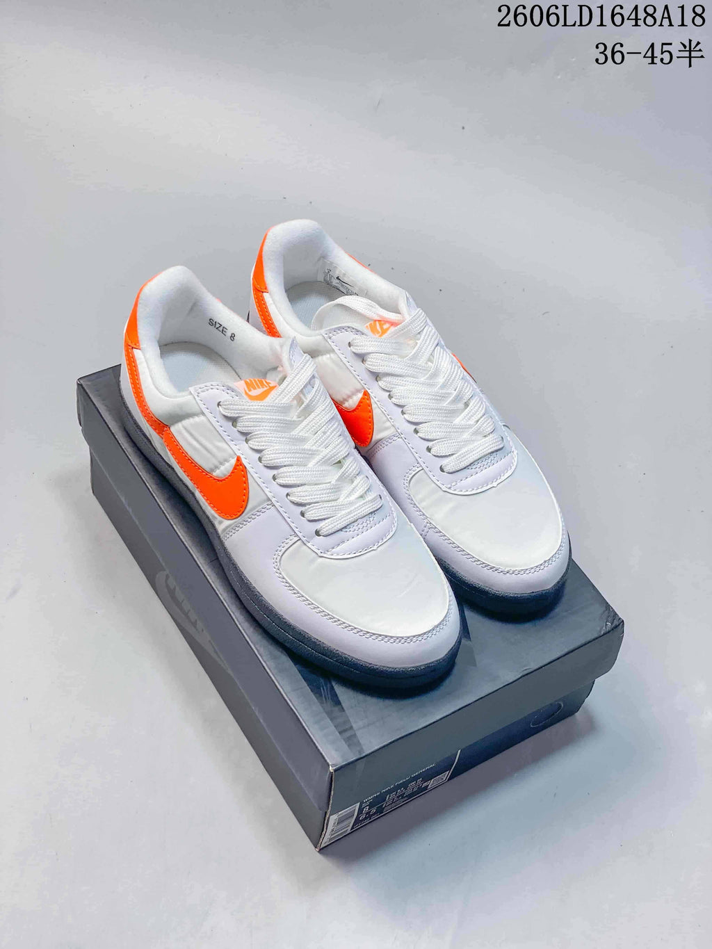 Pair of white and orange Nike Field General 82 SP low-top sneakers on a shoe box