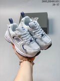 Pair of white and navy New Balance 530 kids' sneakers shown from the front, with a shoebox behind them.