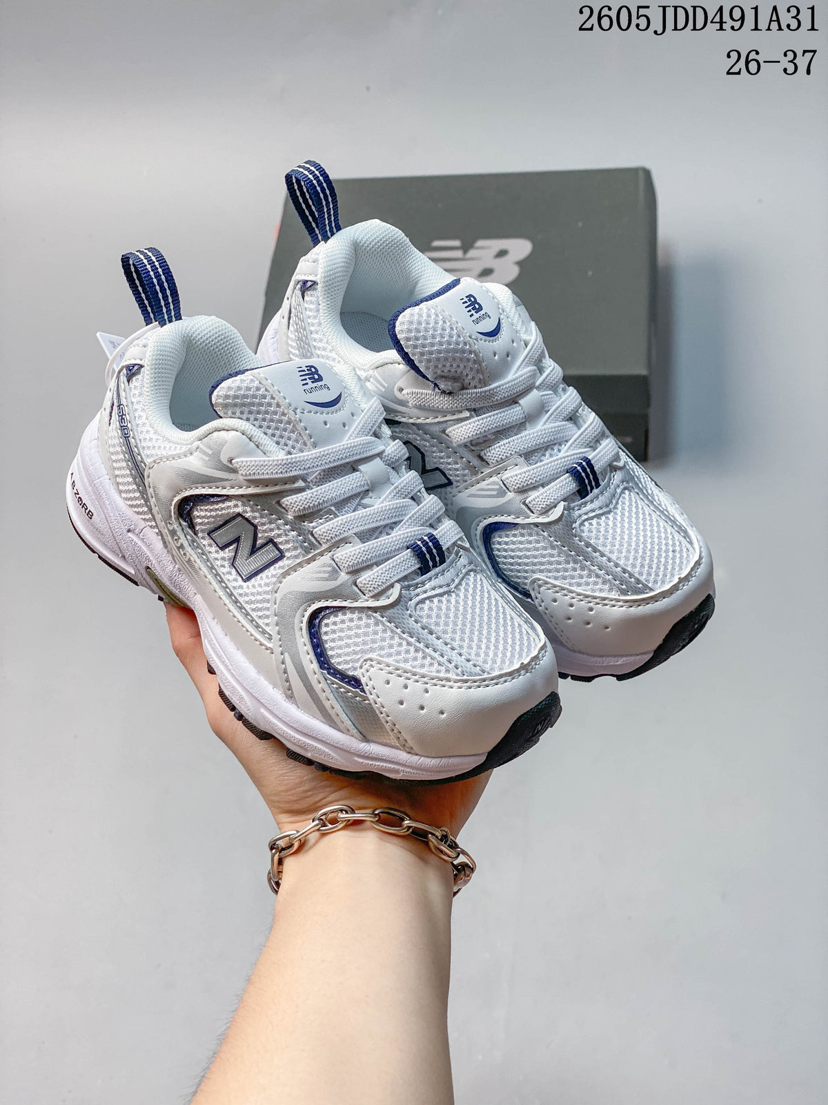 Pair of white and navy New Balance 530 kids' sneakers shown from the front, with a shoebox behind them.
