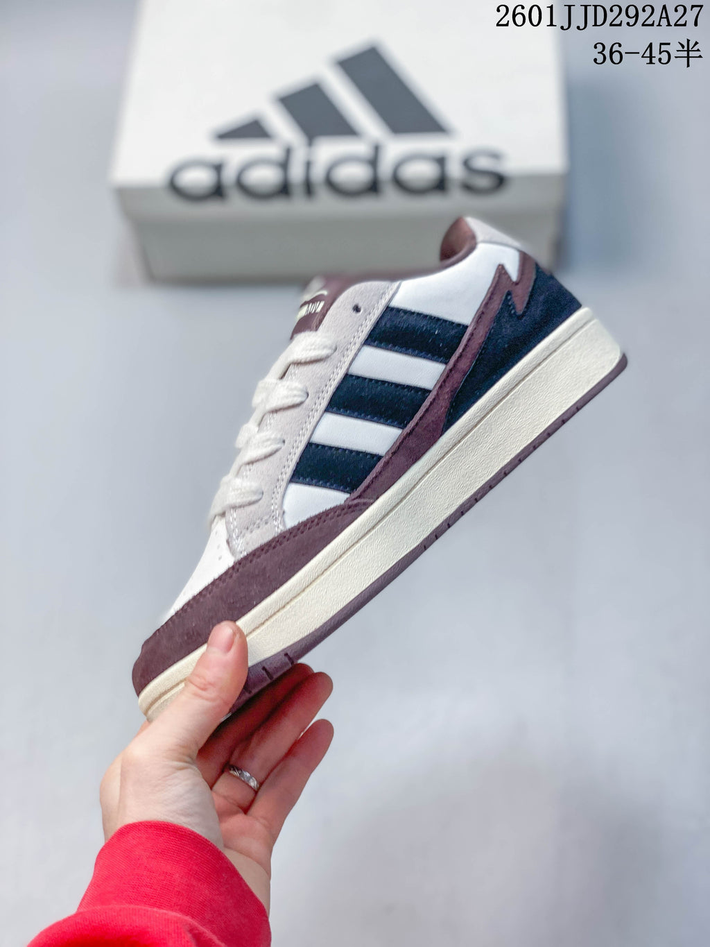 Side profile of an Adidas Wcard Adv sneaker with three navy stripes and a cream-colored sole.
