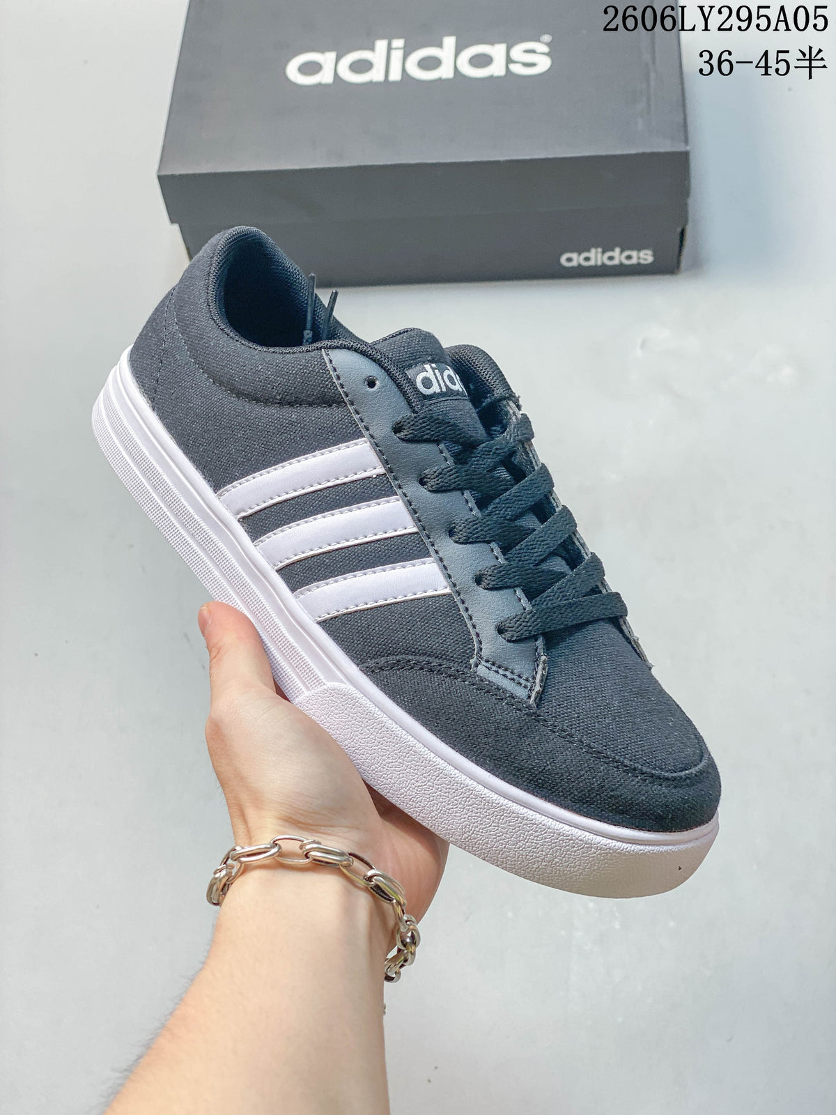 Side view of a charcoal gray adidas low-top sneaker with light stripes and a white outsole.