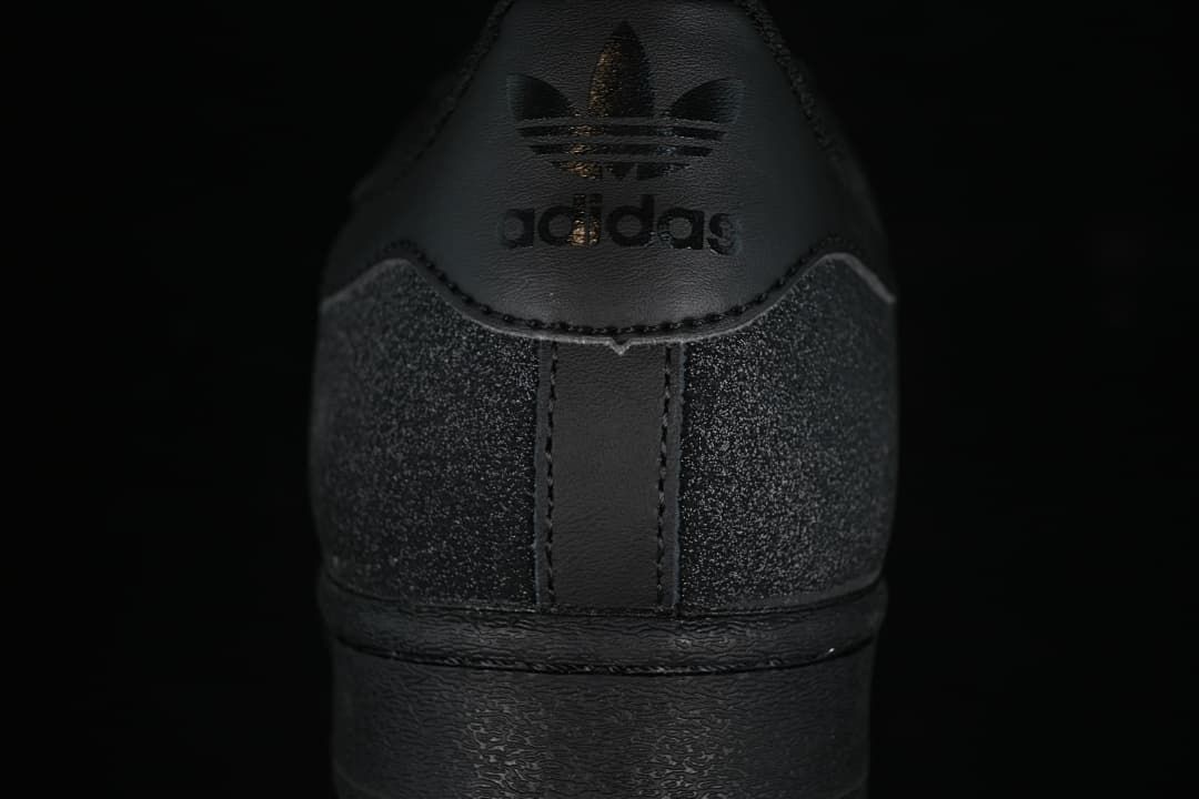 Rear view of the black sneaker with Trefoil branding and speckled heel panels