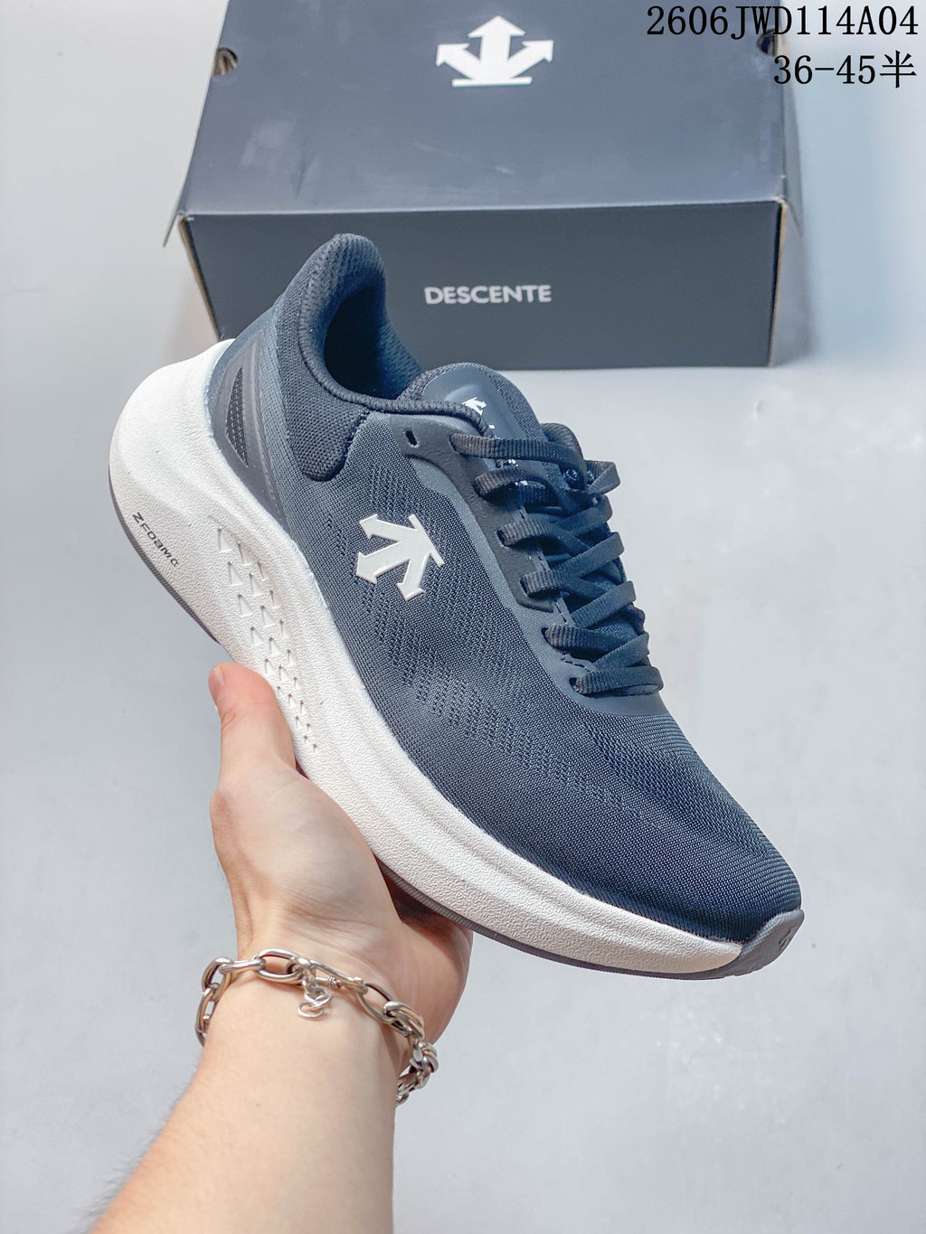 Side view of a blue-gray DESCENTE sneaker with a white midsole and branded side detail.