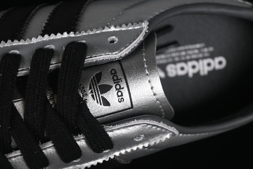 Close-up of black laces, silver eyelet panels, and tongue branding