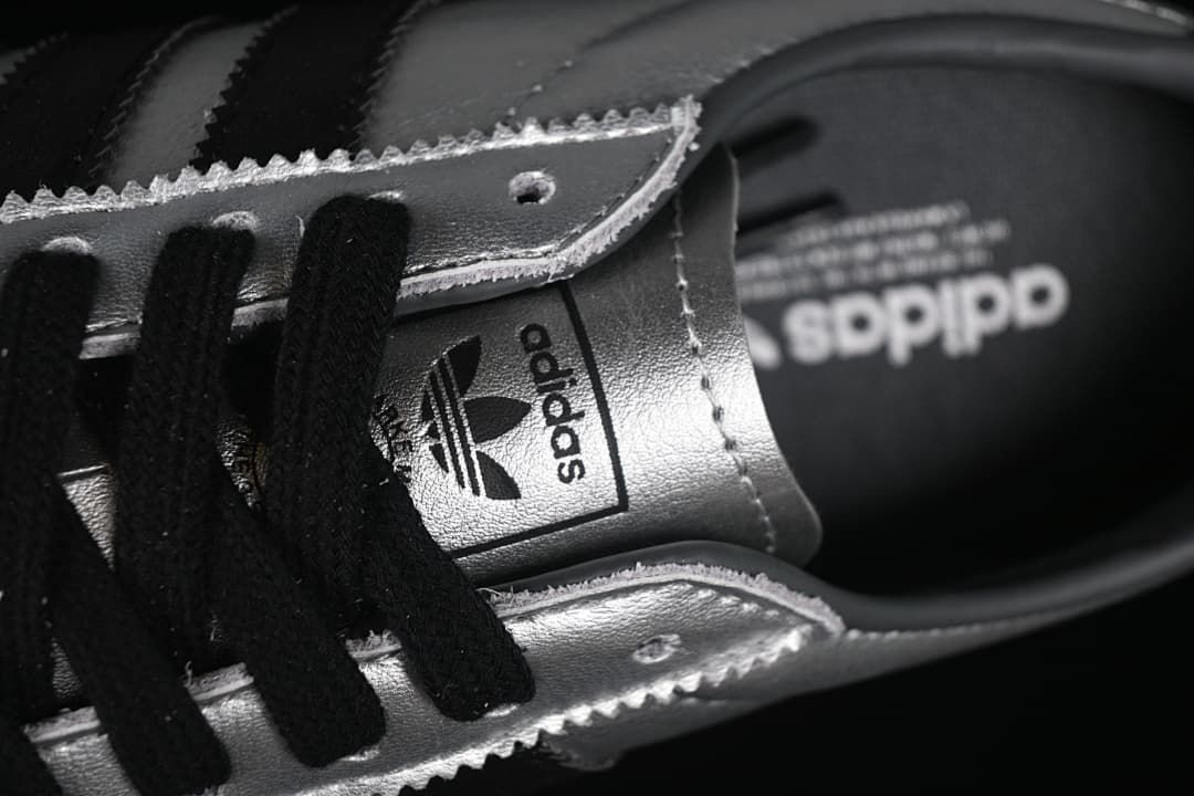 Close-up of black laces, silver eyelet panels, and tongue branding