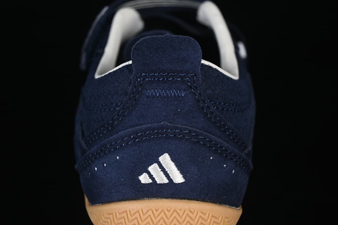 Rear view of the navy sneaker with a white adidas mark and gum outsole.